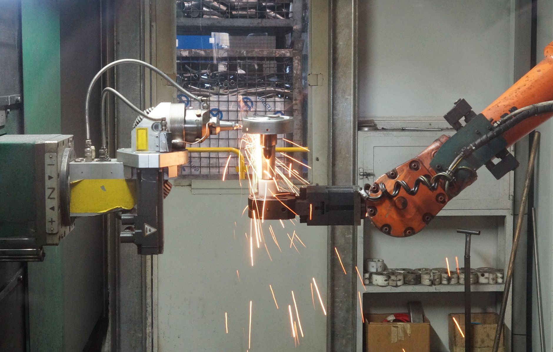 Roboterarm beim Schweißen in einer Industriehalle mit hellen Funken.