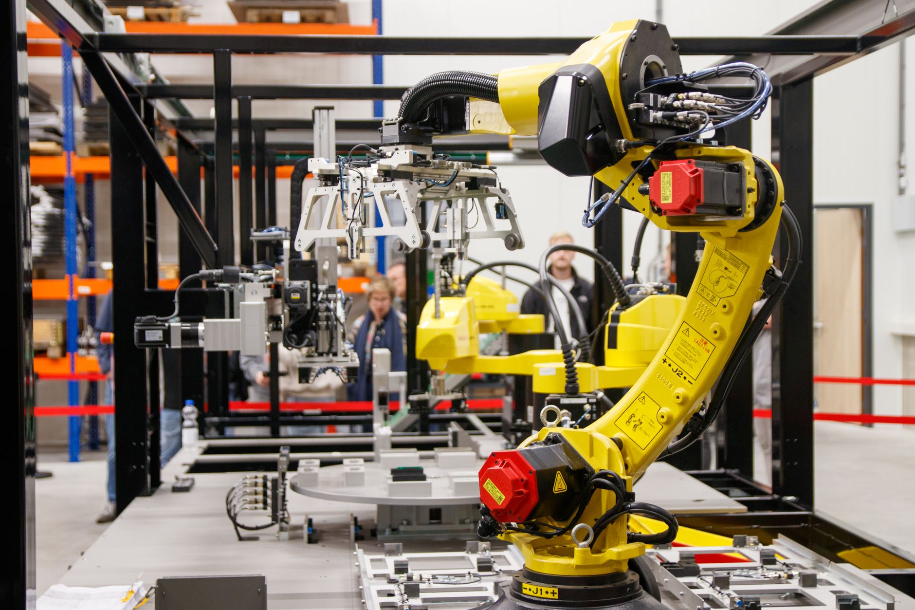 Gelber Industrieroboterarm bei der Arbeit in einer modernen Fertigungshalle.
